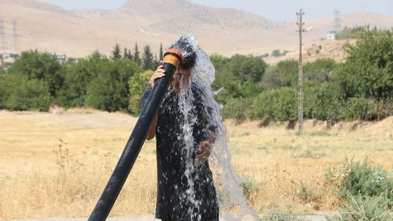 Mardin'de sıcaktan bunalan vatandaş tarım sulama hortumu ile serinledi